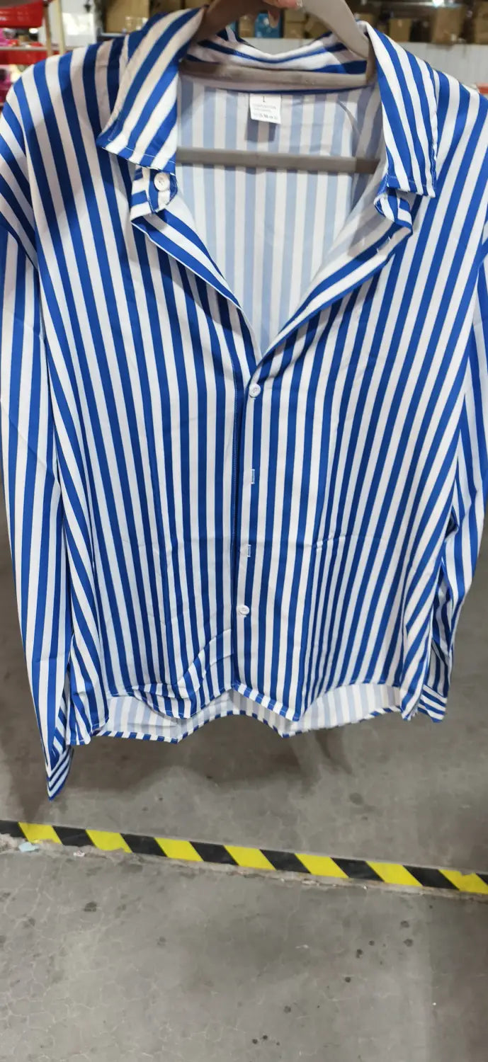 Chemise décontractée à manches longues rayée verticalement bleu et blanc pour hommes, à patte boutonnée et col, suspendue sur un cintre en bois.