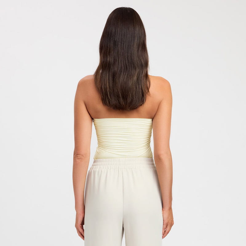 A soft pale yellow strapless keyhole crop top with ruched detailing and a smooth satin-like finish.