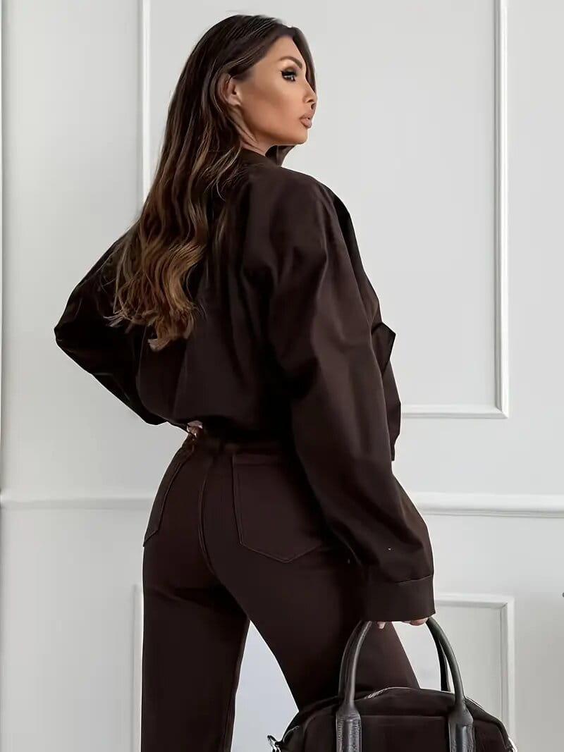 Black structured handbag with sleek handles and minimalist design displayed alongside brown high waisted flared jeans.