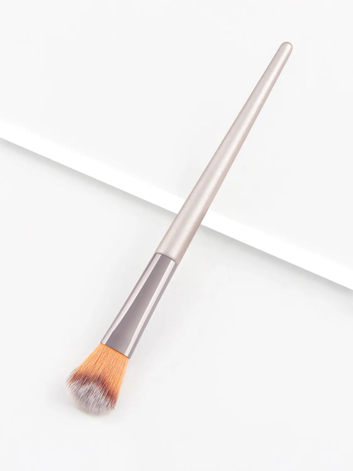 A sleek metallic silver finger belly makeup brush with a tapered handle and soft bristles transitioning from orange to gray for professional contouring.