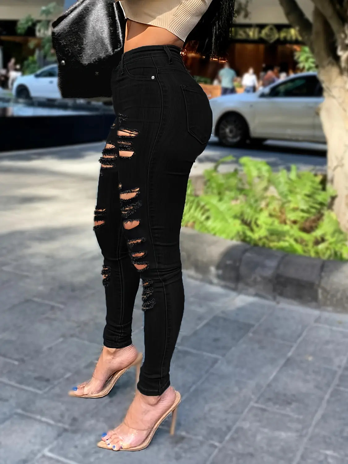 Jeans skinny taille haute échancrés noirs présentant un tissu délavé en denim noir.
