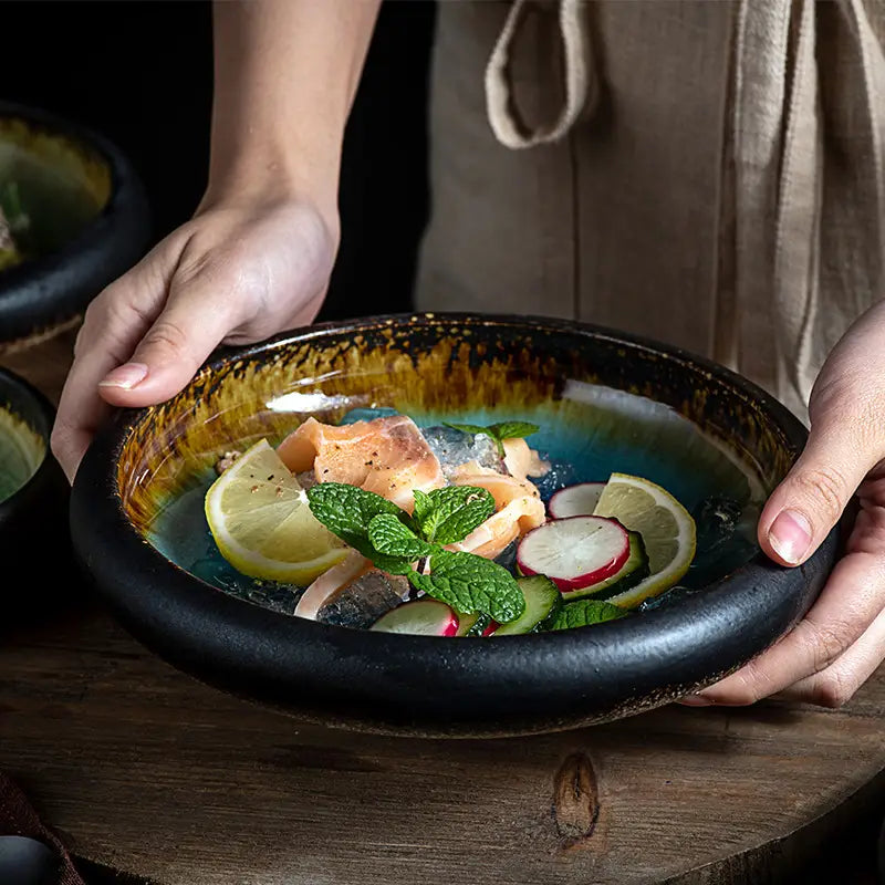 Rustic ceramic bowl kiln glazed bone china round plate with a glossy black exterior and a vibrant hand-painted interior featuring swirling teal and gold glaze.