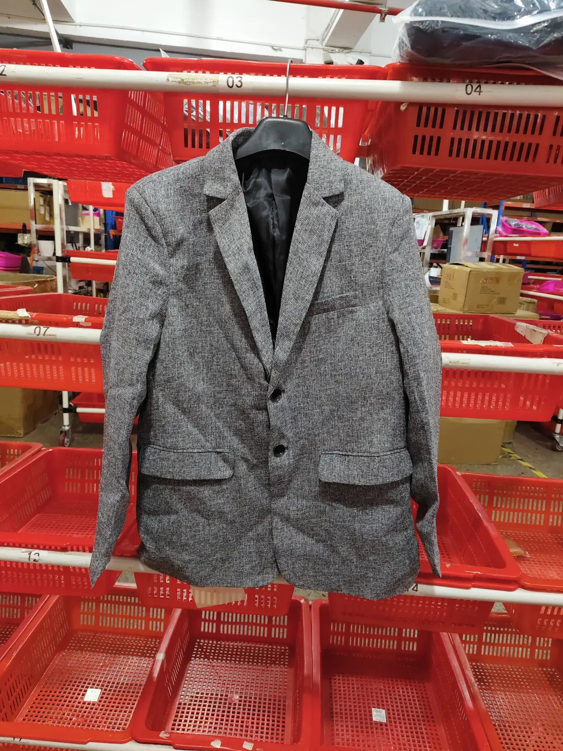 Men’s casual thin blazer spring jacket in gray textured fabric with black inner lining hanging on a mannequin in a retail store setting.