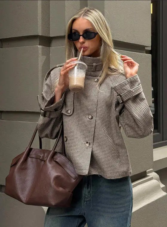 Brown leather tote bag with a structured slightly slouched silhouette and visible stitching details featured alongside a houndstooth coat relaxed fit double breasted jacket.