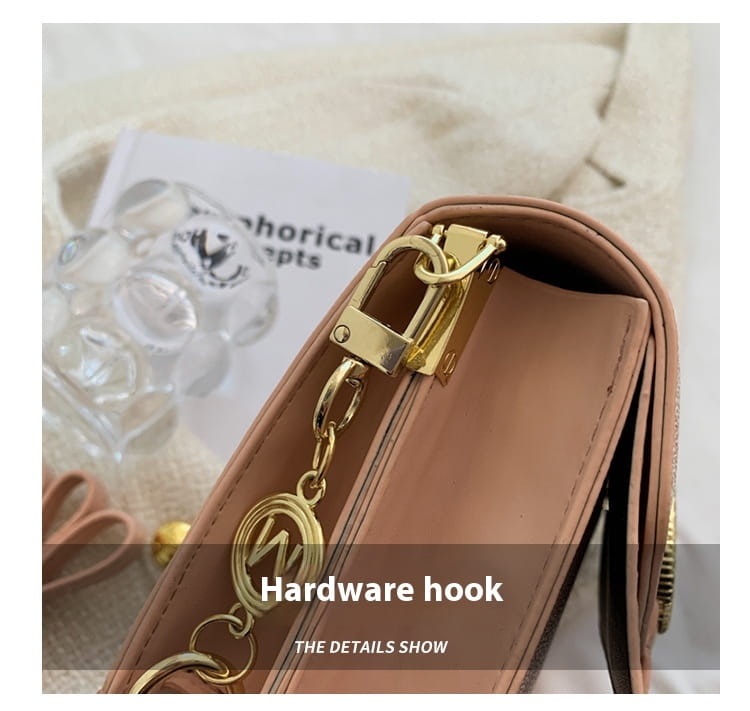 gold-toned hardware hook with chain and circular emblem attached to a tan leather strap of monogram letter print crossbody messenger bag
