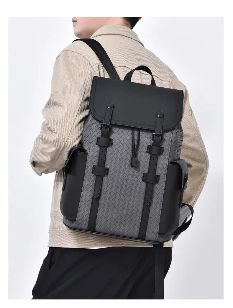 Men’s leather business travel backpack with laptop sleeve in black and gray woven leather featuring a structured design with black straps and buckles.