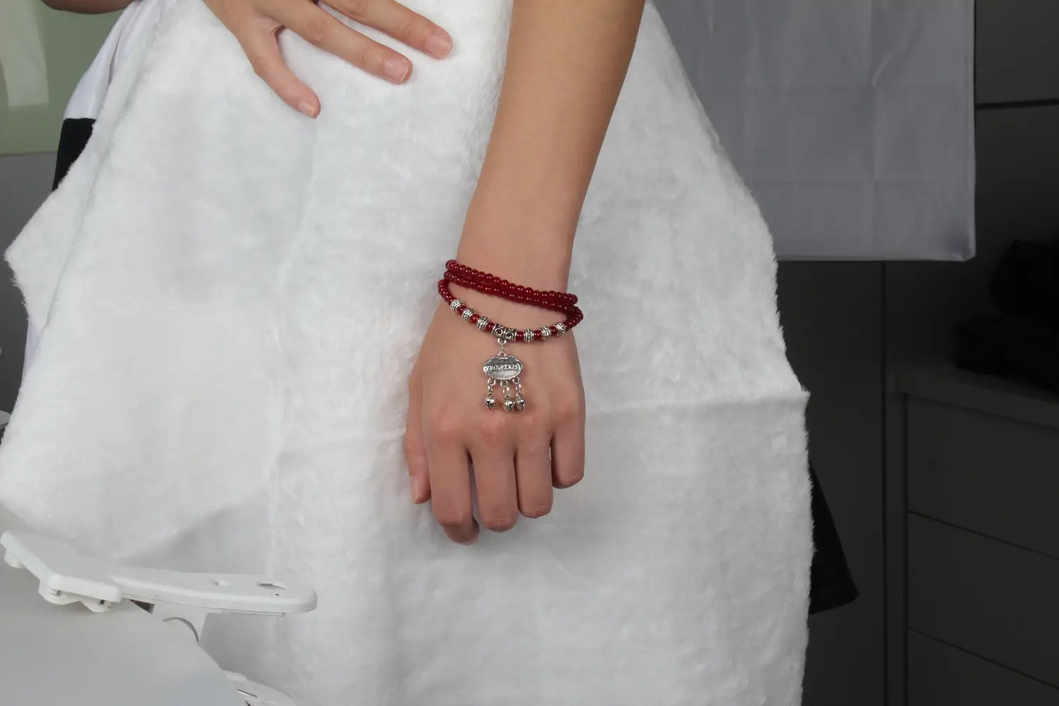 A delicate red agate beaded bracelet with a silver-toned engraved protect charm pendant designed for good luck.