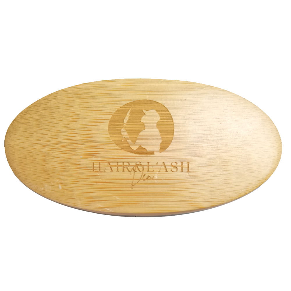cepillo ovalado de bambú de color claro con logotipo y nombre de marca sutilmente grabados, incluido en un kit de crecimiento de barba con dermaroller y herramientas de aseo.
