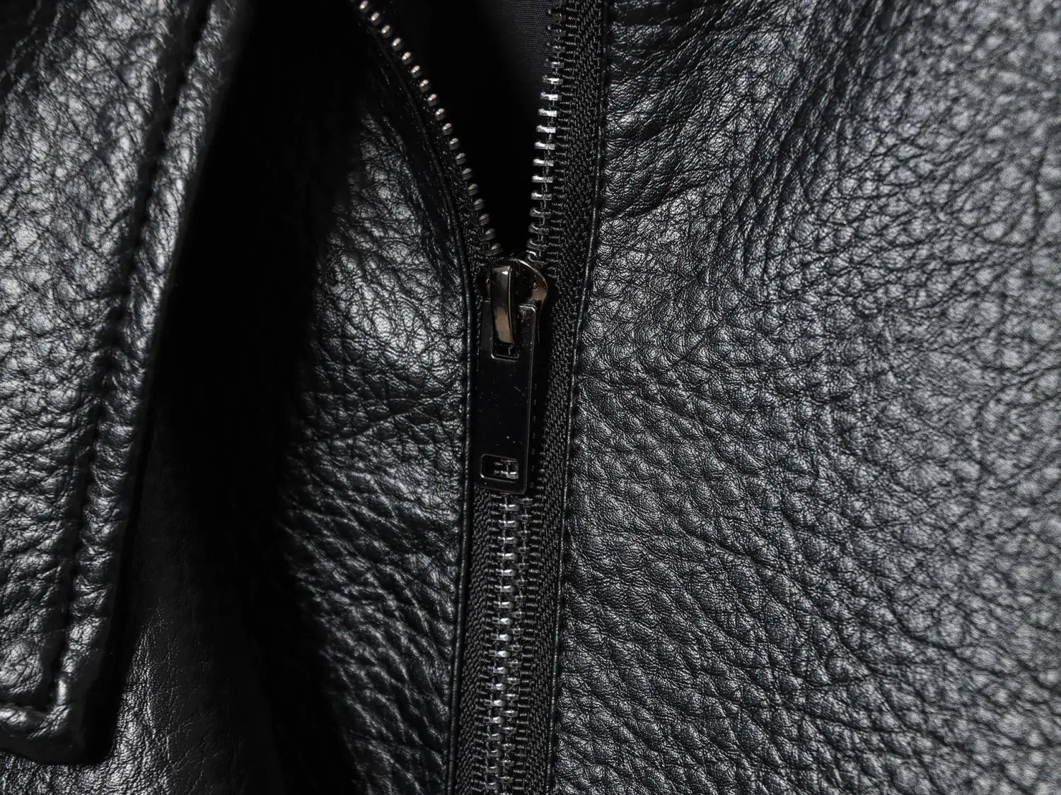 Schwarze Damen-Motorradjacke mit hohem Stehkragen aus Kunstleder, mit schwarzem strukturiertem Lederreißverschluss und metallischem Ziergriff.