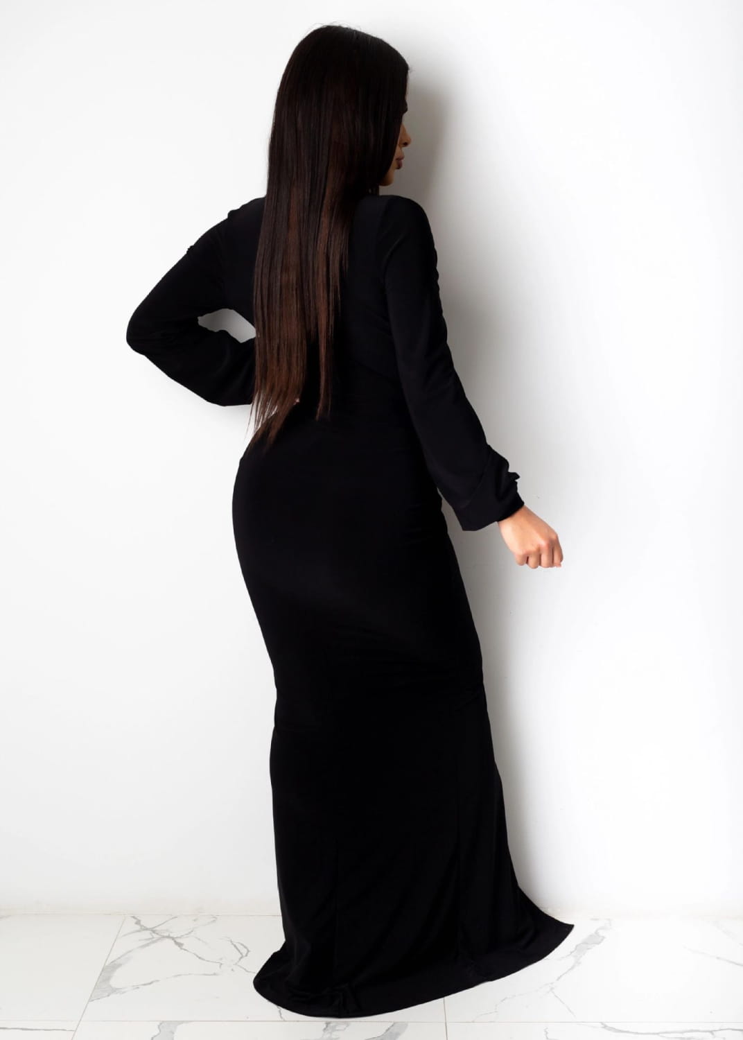A sleek black velvet long-sleeved maxi dress with a fitted silhouette and flowing hem designed as a velvet v neck evening dress.