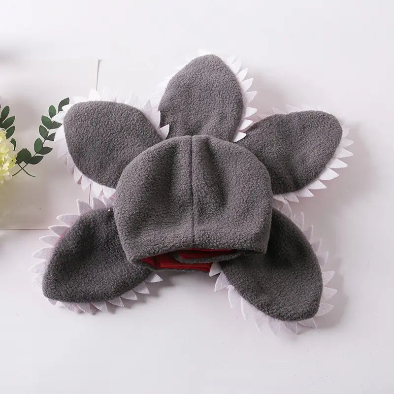 gray plush shark-shaped dog hat with white spiked edges and red interior lining designed as a carnivorous flower pet costume