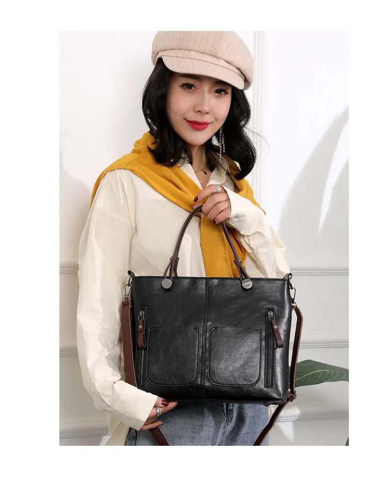 Black leather tote crossbody bag with brown straps and zipped pockets featuring large retro capacity.
