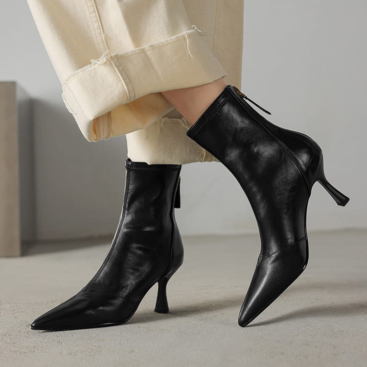 Black leather pointed toe cowhide stiletto ankle boots with a slim high heel and zipper closure.