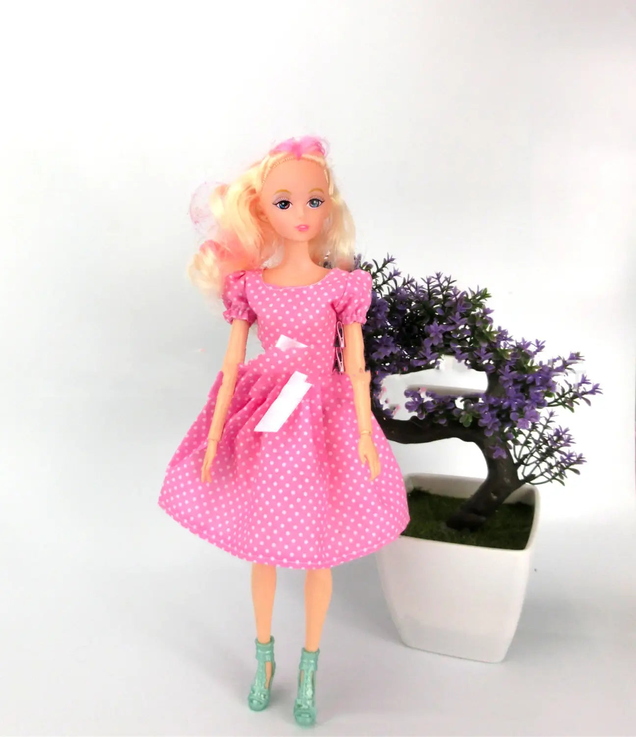 Eine blonde Barbie-Anziehpuppe in einem pinkfarbenen Fashion-Set mit Punkten mit puffigen Ärmeln und türkisfarbenen High-Heels für Kinder.