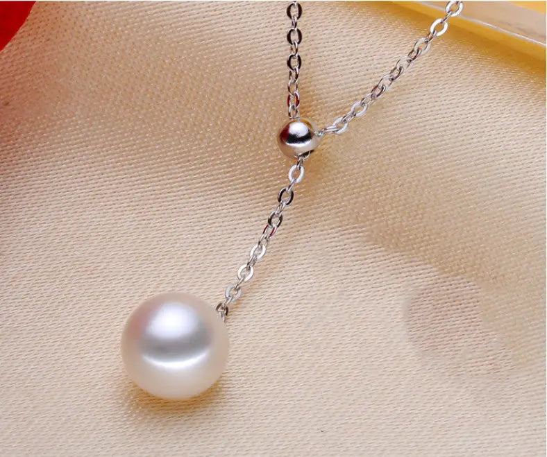 A delicate silver adjustable pearl lariat necklace featuring a single lustrous white pearl pendant and a small spherical accent bead.