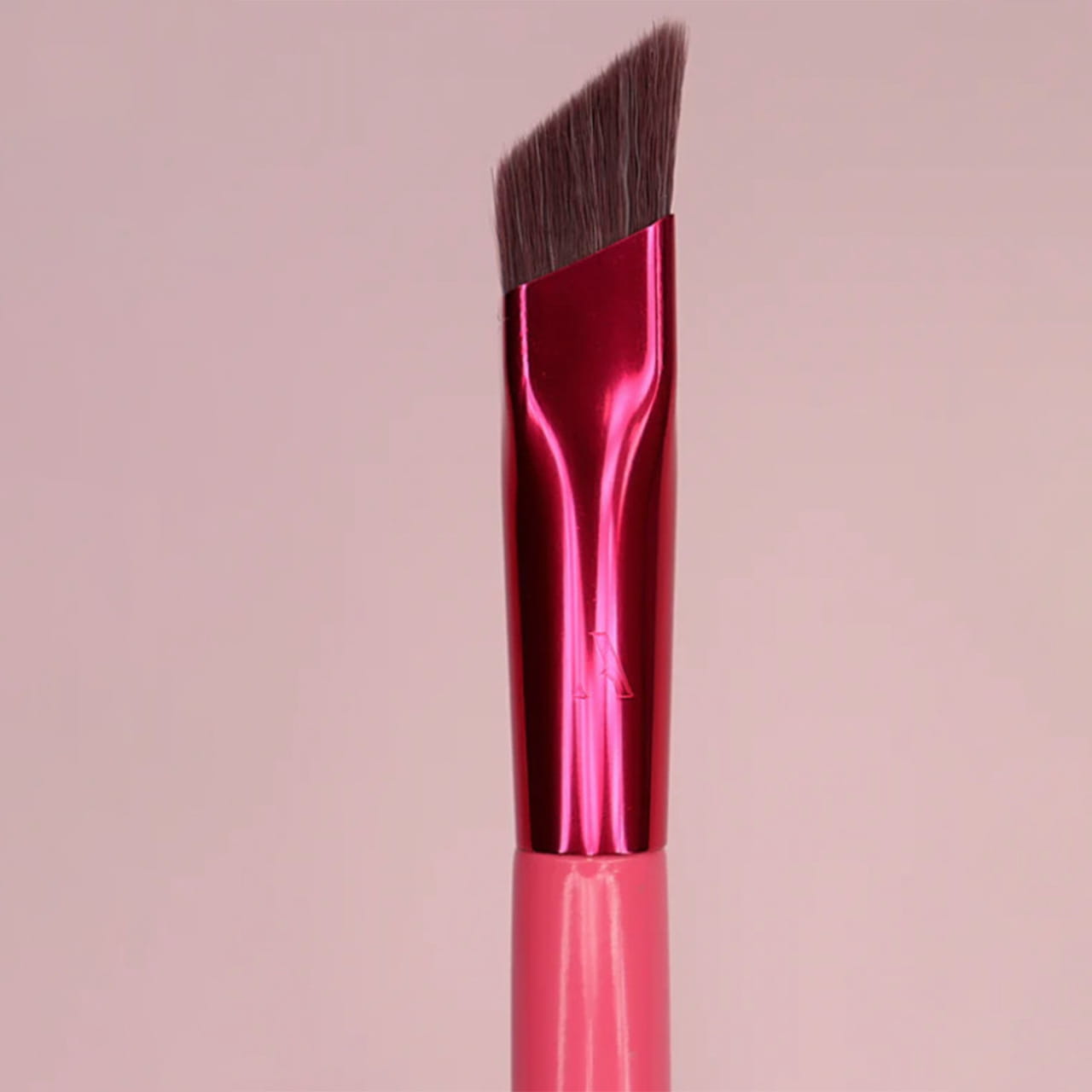 Eyebrow brush with vibrant pink angled applicator featuring a glossy metallic finish and dense dark brown bristles for precise gel application.