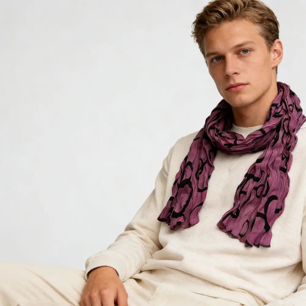 un foulard en polyester froncé fuchsia, présentant une couleur mauve souple, avec un motif abstrait noir fluide, drapé autour du cou