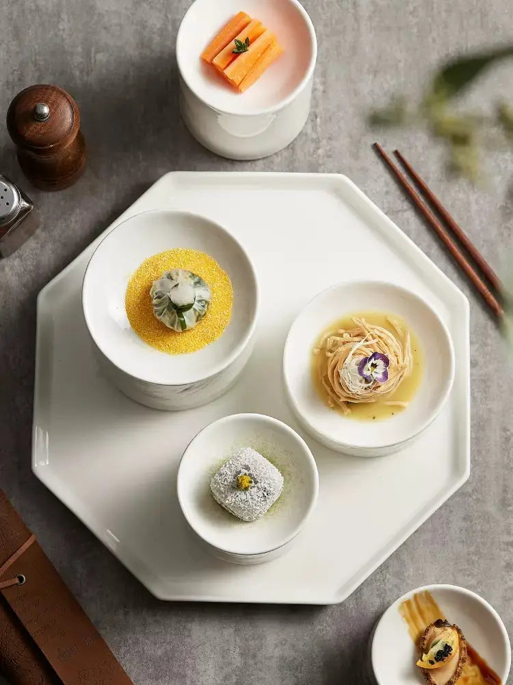White octagonal ceramic serving tray with smooth glossy finish and subtle rim detailing from ceramic appetizer bowl set with matte textured finish.