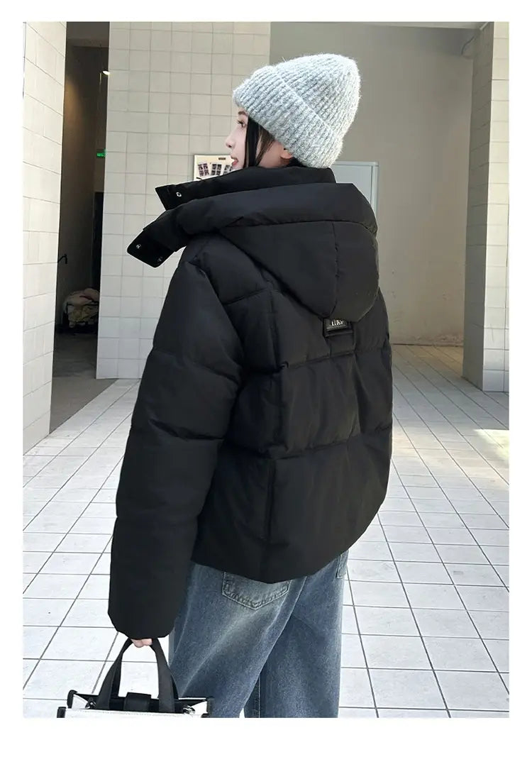Veste courte matelassée à capuche pour femme noire, avec design matelassé et petit écusson de marque au dos, conçue pour l’habillement d’hiver chaud, présentée de l’arrière