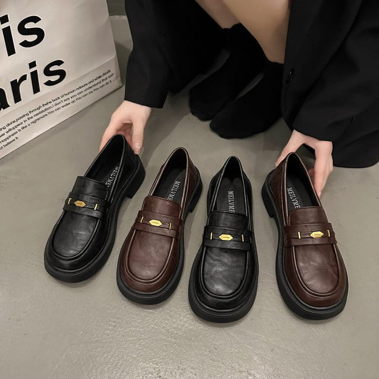Black and brown leather loafers with gold-tone metal buckles featuring elegant buckle detail.