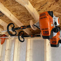 Ceiling mounted birch plywood weed wacker storage rack holding an orange and black Stihl string trimmer