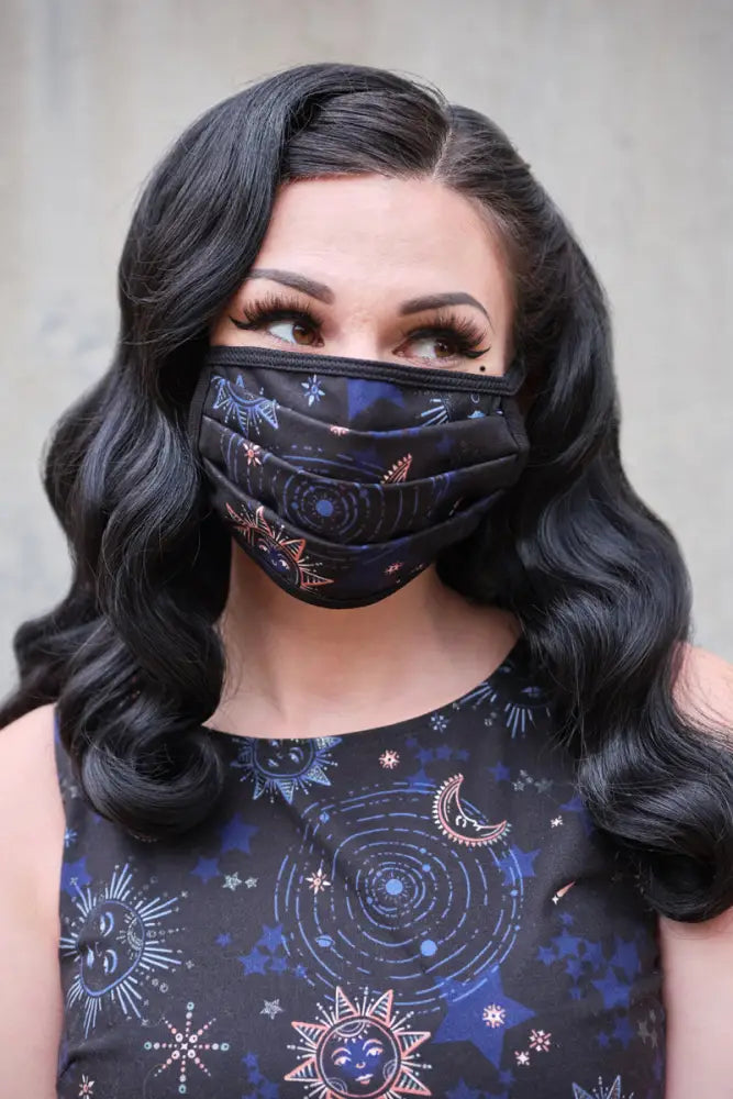 Black reversible cotton pleated face mask with celestial pattern of suns moons stars in blue pink and white shades