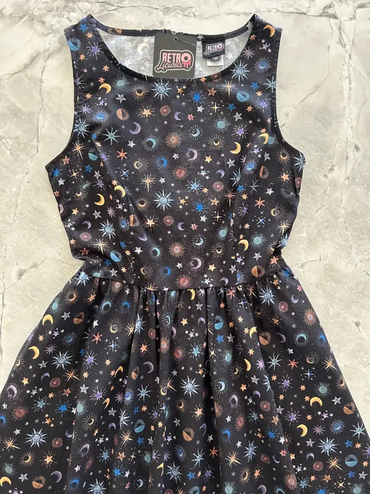 Black sleeveless 1950s cotton midi dress with vibrant cosmic print and pockets featuring stars moons and suns