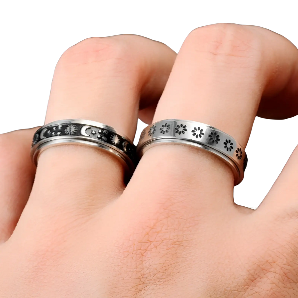 Two silver-toned stainless steel spinner rings engraved with celestial and floral patterns for anxiety relief