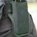 Dark green suede phone holster with white stitching and black strap shown from the back with belt loop and card slots