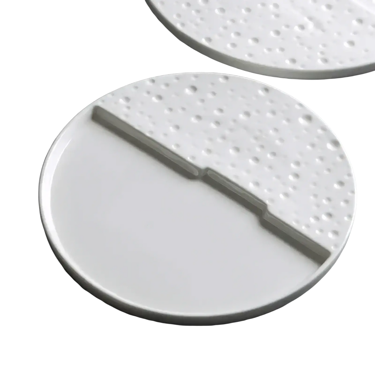 White ceramic decorative plate with textured dotted half and smooth half separated by a raised dividing ridge