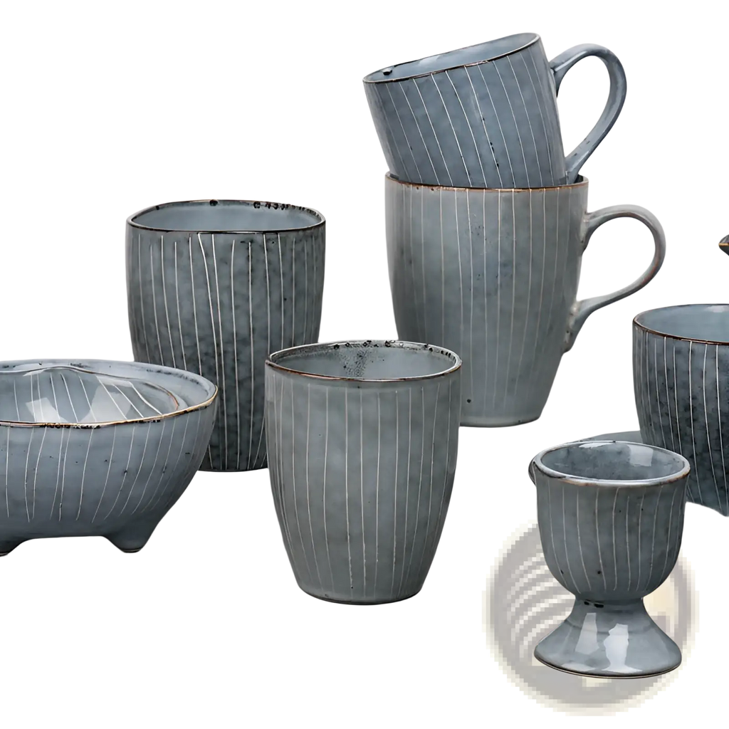 A collection of handcrafted ceramic mugs and bowls in muted blue-gray glaze with ribbed texture and rustic brown rims