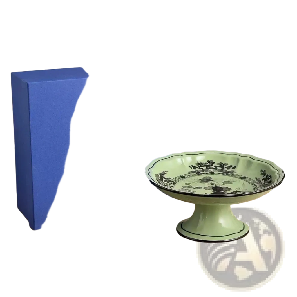 A delicate mint green ceramic dessert bowl with fluted rim and black floral pattern beside royal blue gift box