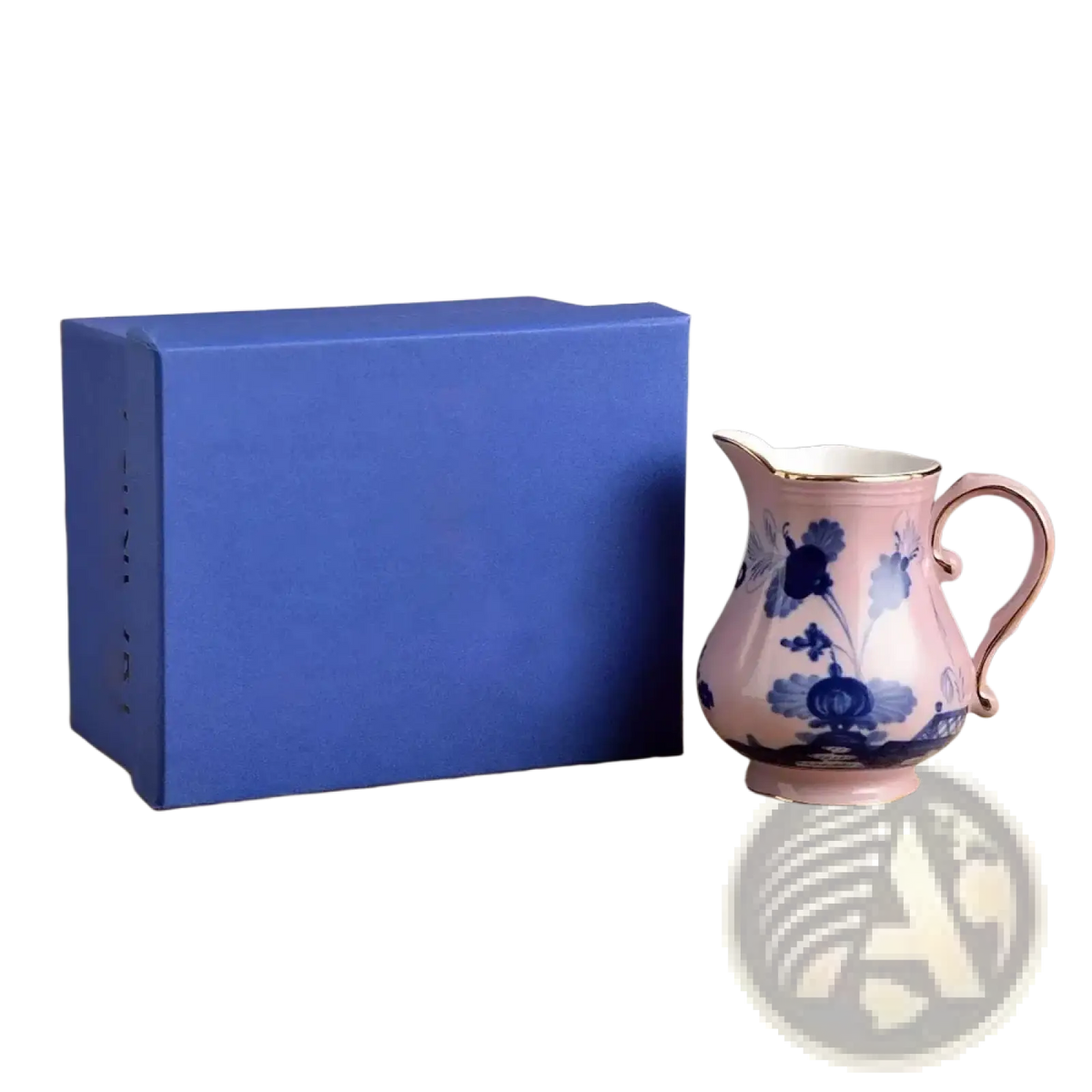 A delicate pink ceramic pitcher with blue floral patterns and gold rim beside a royal blue gift box in a ceramic tableware set