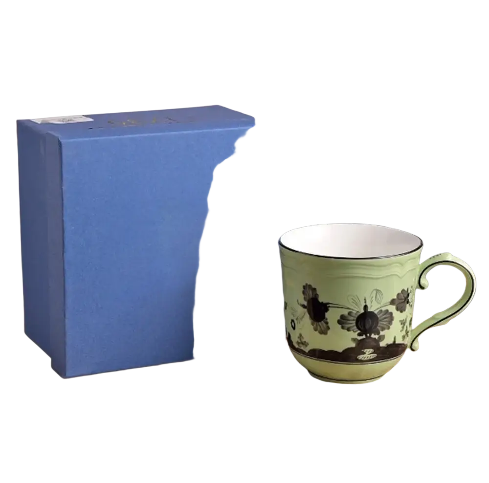 A light green ceramic coffee mug with black floral and bird design and matching handle from a tableware set