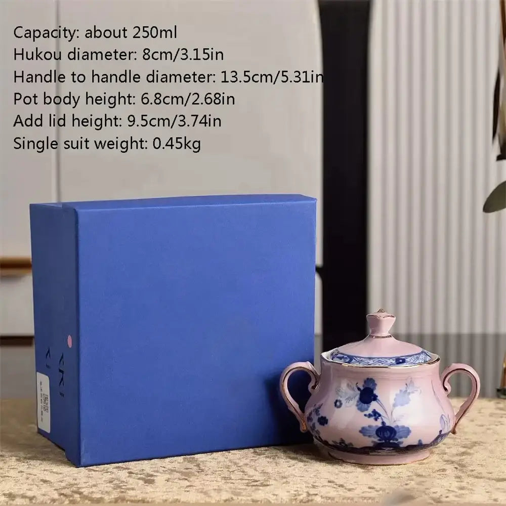 Pink ceramic sugar bowl with blue floral patterns gold trim two handles and matching lid from ceramic floral tableware set