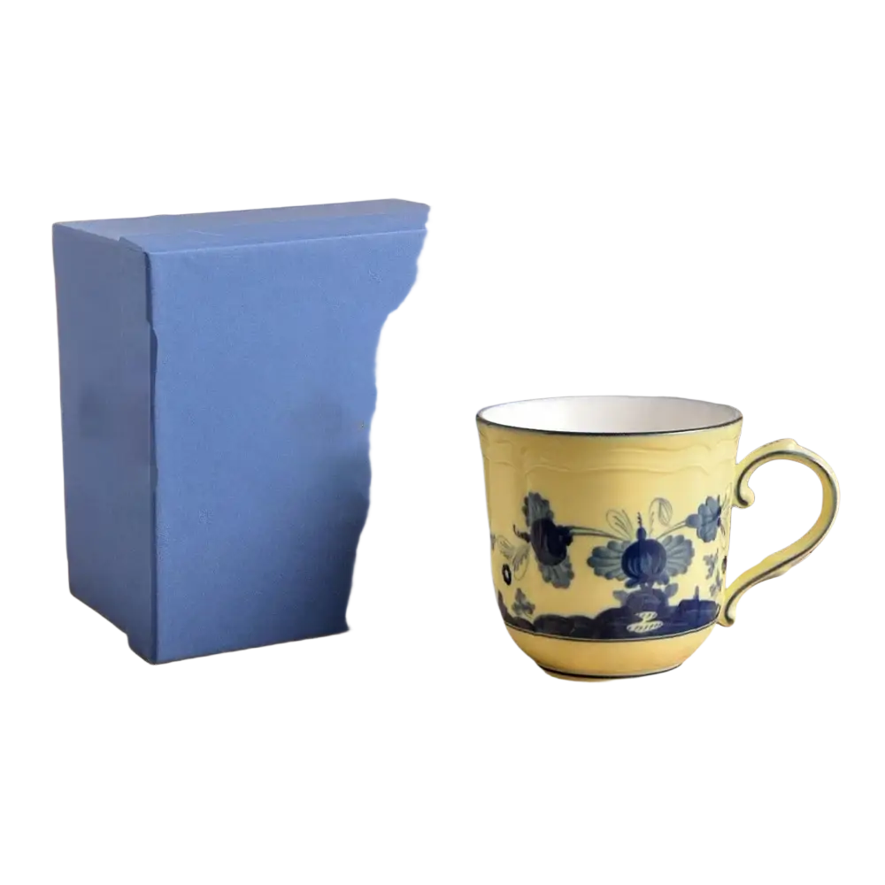 A yellow ceramic floral tableware coffee mug with blue bird patterns, white interior, and curved handle