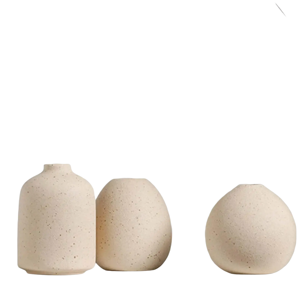 Three beige speckled ceramic flower vases of varying rounded shapes for boho tabletop decor on a white shelf