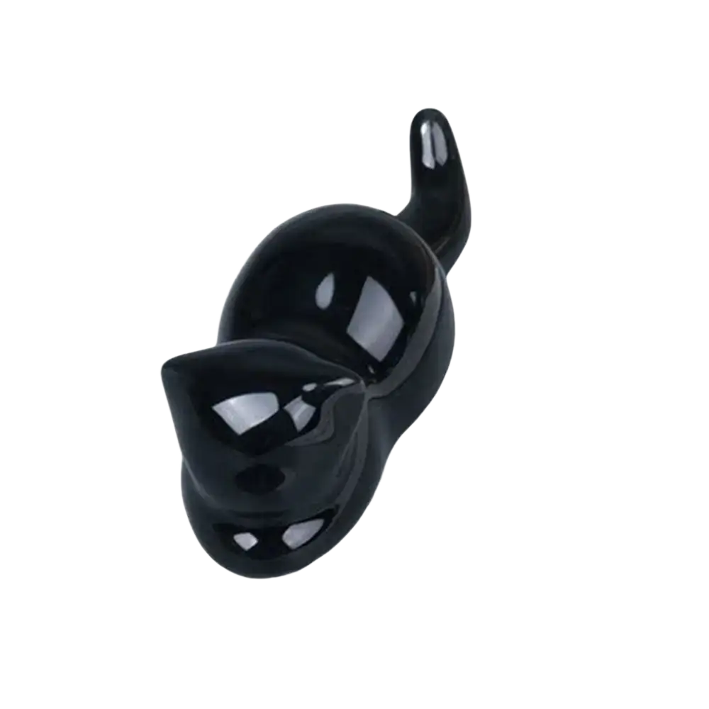 A glossy black ceramic pen holder shaped like a cat with smooth contours and a curved tail for brush rest