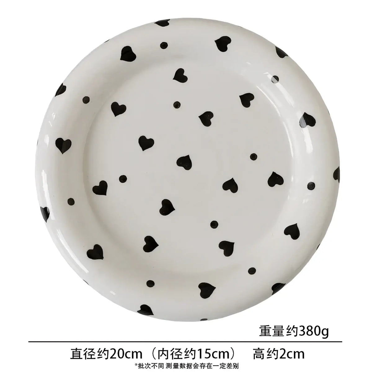 White ceramic plate with glossy finish featuring black heart and dot patterns in decorative kitchenware set