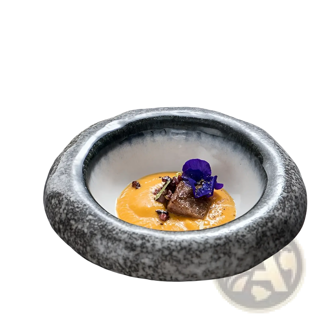 A speckled gray ceramic sashimi bowl with a smooth rim holds orange puree topped with a purple edible flower