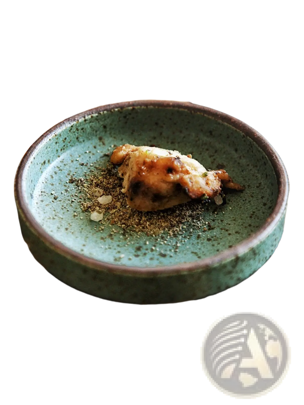 A rustic green ceramic sauce dish with speckled glaze and dark brown rim holding a small portion of food