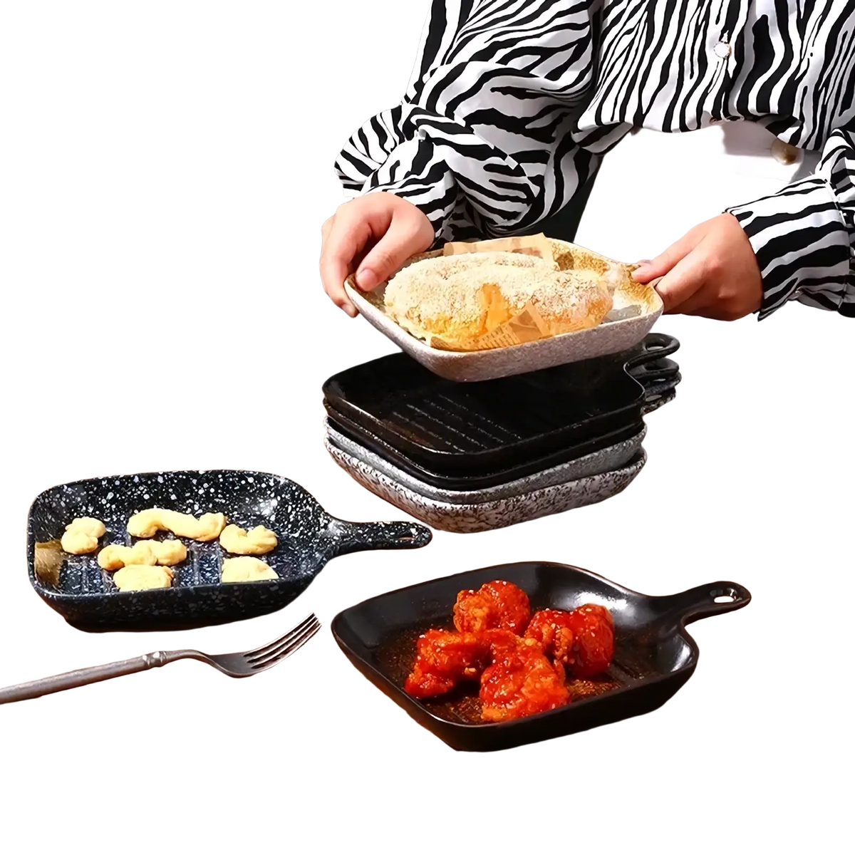 A speckled gray cast iron skillet with handle held by person in zebra print shirt alongside ceramic square baking plate with handle