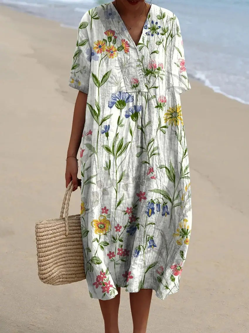 A flowing white vibrant floral V-neck short sleeve maxi dress adorned with a colorful pattern in shades of yellow pink blue and green.