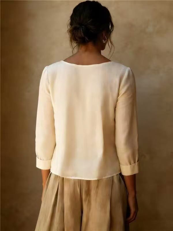 Une blouse ample en lin et coton pour femmes, couleur crème, avec un tissu léger, des manches à la longueur trois-quarts et des poignets retroussés.