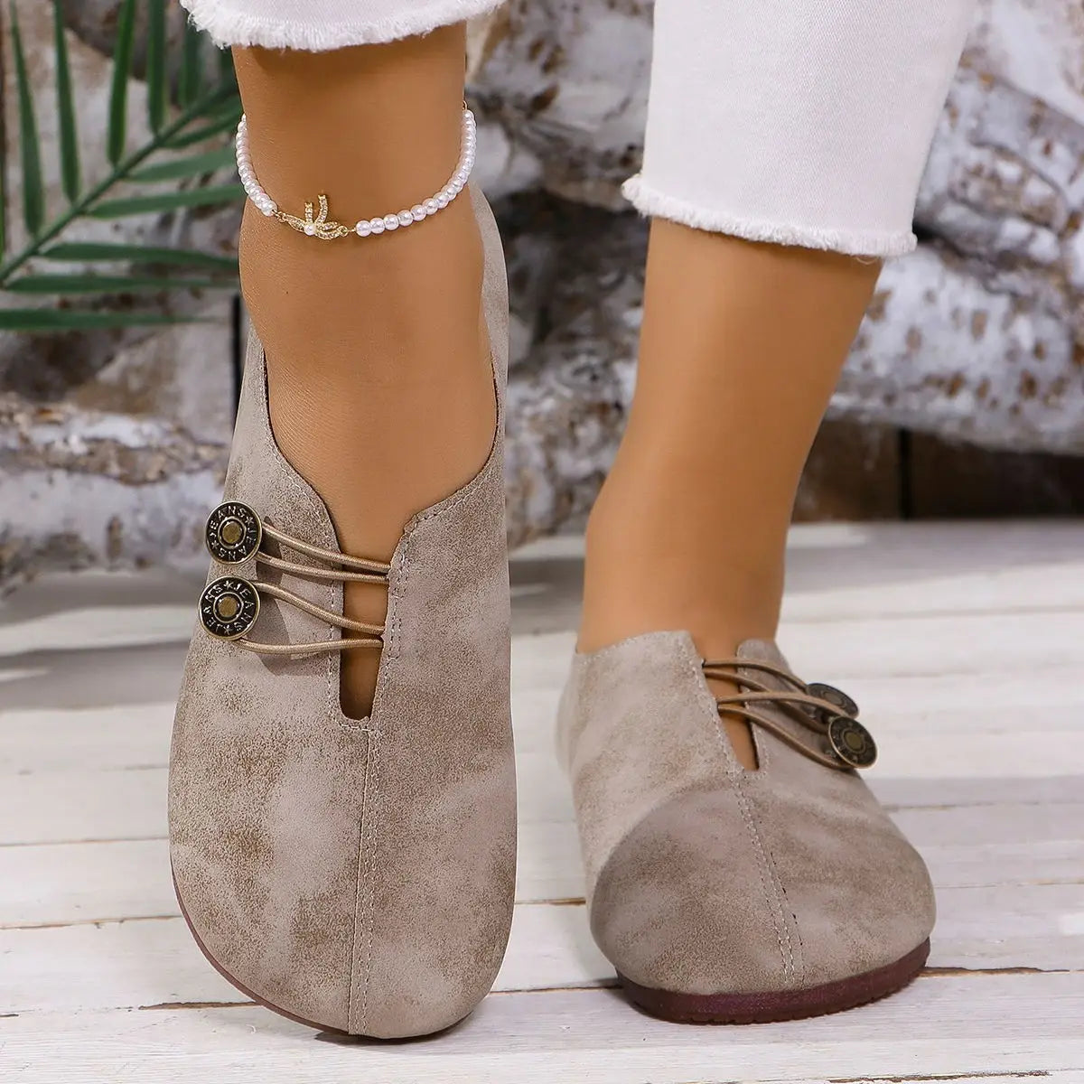 beige suede slip-on women’s loafers with square toe, lace-up leather details, and two decorative metal buttons.