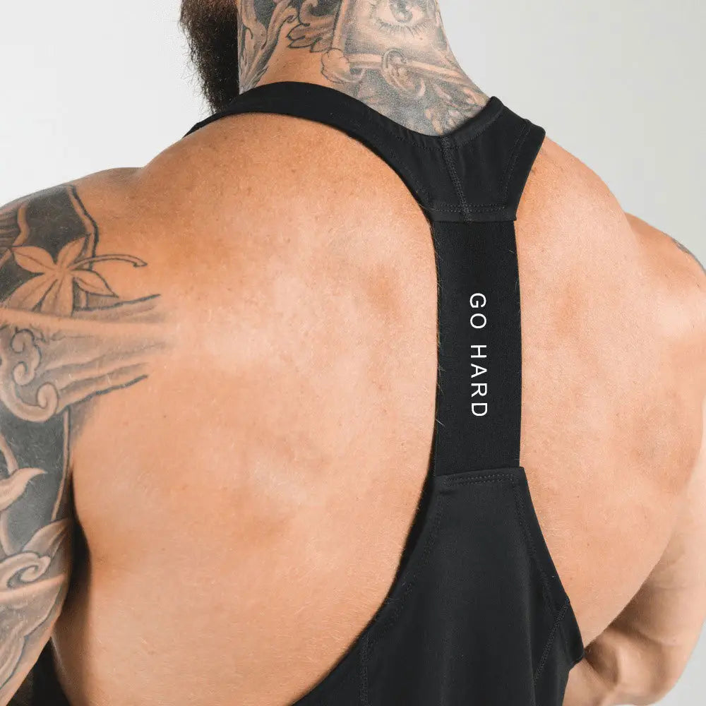 Men’s black racerback athletic tank top showing the back side with go hard text on the strap.