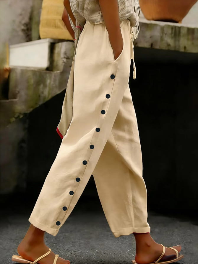 Cream-colored loose-fitting cropped patchwork button casual pants for women featuring a row of dark buttons down the side seam and subtle red trim at the hem.