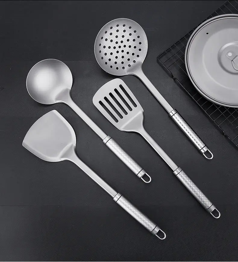 Lot de quatre ustensiles de cuisine en acier inoxydable, comprenant une spatule pour wok en titane avec des poignées texturées et une louche perforée.