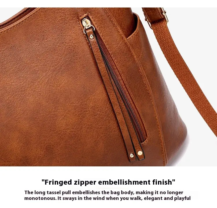 Brown leather hobo bag with tassel, front zipper pockets, fringed zipper pull, and gold-tone hardware made of faux leather.