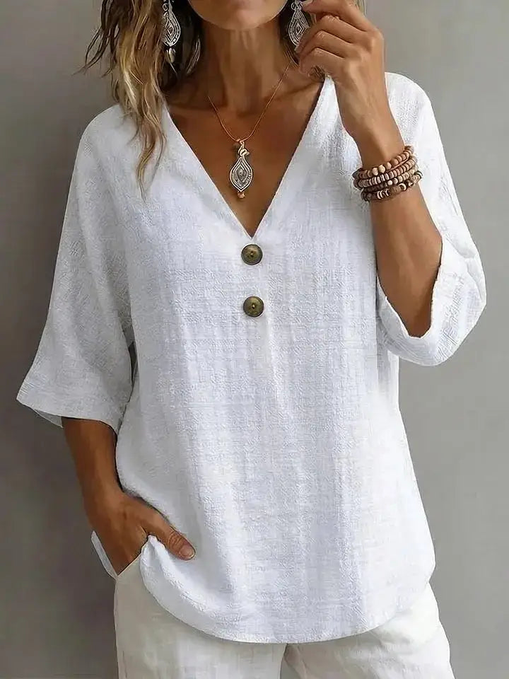 White linen blouse with three-quarter sleeves and olive green buttons featured in a linen V-neck button top.